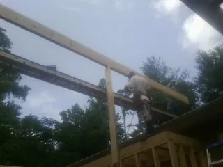 Carpenter setting a ridge beam over a new addition frame — Ice Dam Removal by Roofing Brothers in Morenci