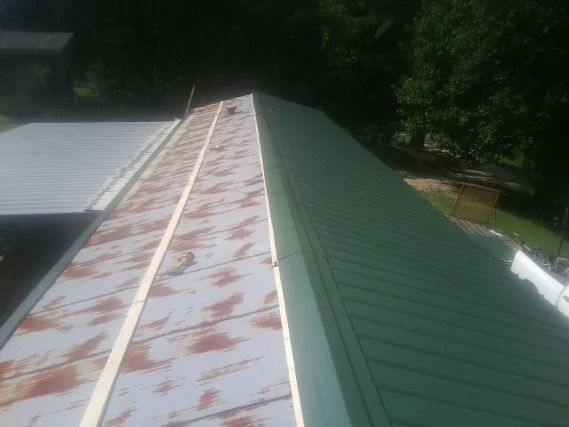 Old rusted panels beside newly installed green metal roofing — Wind Damage Roof Repair by Roofing Brothers in Morenci