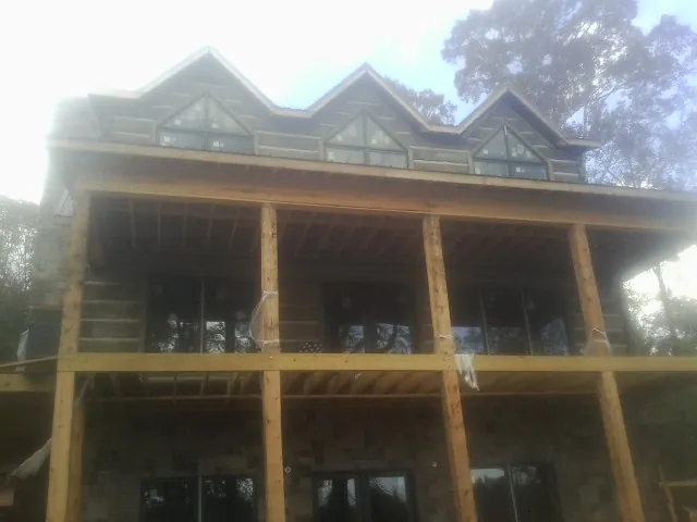 Dormers and porch framing on a large log home under construction — Roof Coating work by our crew in Morenci