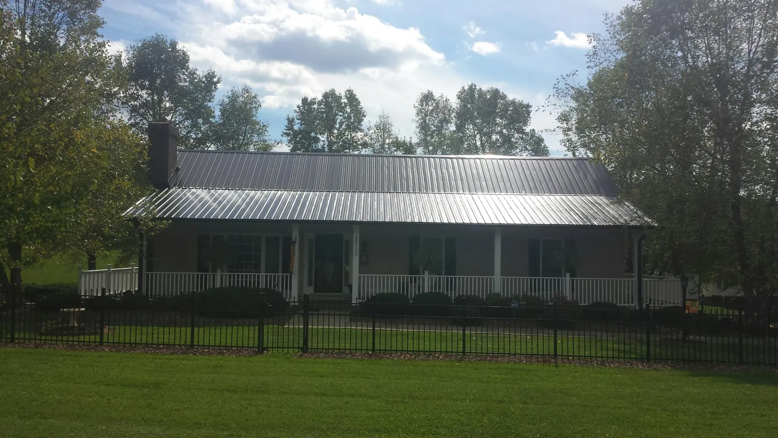 Gray metal roof on a brick ranch with a full width front porch — Gutter Guard Installation work by our crew in Morenci