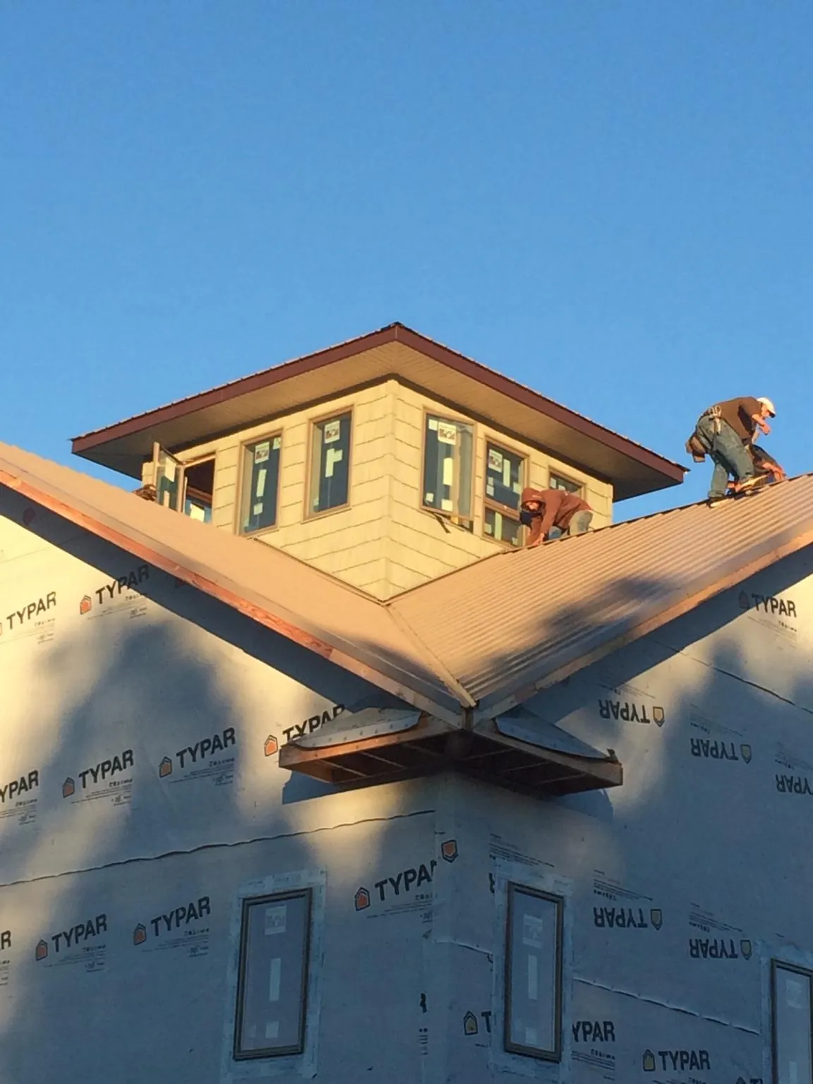 Roofers working around a rooftop cupola on a new metal roof at sunset — Roof Waterproofing in Morenci by Roofing Brothers